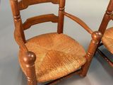 a pair of antique wooden chairs with cane back cushions