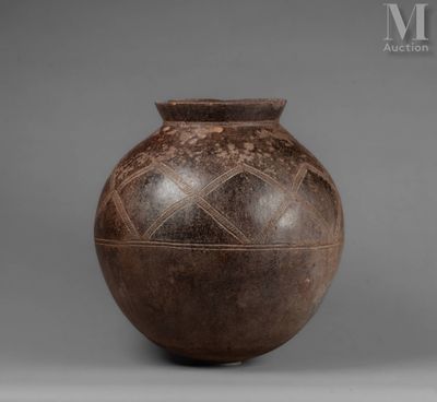 an old brown vase sitting on top of a table next to a gray wall