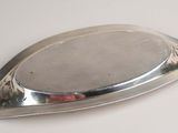 an antique silver plate on a white table with a red flower