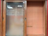 a wooden cabinet with a glass door and a red wall