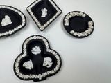 four pieces of black and white glass with white designs on them