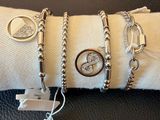 trois bracelets et une bague posés sur un coussin, avec une étiquette de prix