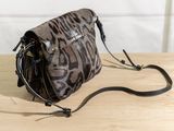 leopard print cross body bag on wooden table with black strap