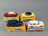 four toy cars are sitting in a box on a gray surface