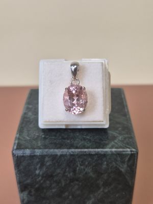 a close up of a pink stone pendant on a white box