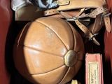 a brown leather box filled with books and a leather ball