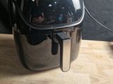 une friteuse à air chaud noire et argentée posée sur une table en bois