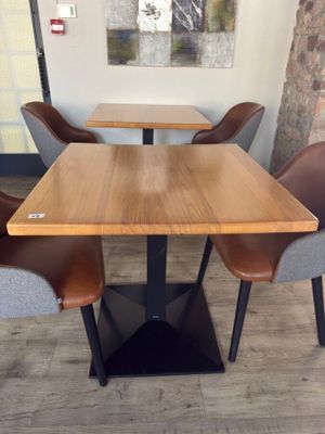 tables and chairs in a restaurant with a painting on the wall behind them