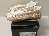 des chaussures adidas posées sur une boîte, sur une surface blanche