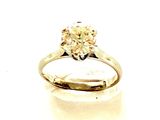 une photo d'une bague sertie d'un diamant jaune posée sur une surface blanche