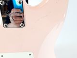 the back of a pink electric guitar with a white background