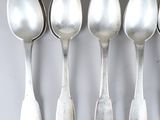 six silver spoons are lined up in a row on a table