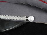 grey uniform hat with a red ribbon and a silver button