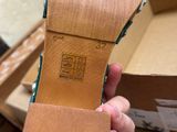 someone is holding up a pair of shoes in front of a box