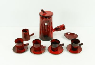 a red coffee pot and cups on a white table