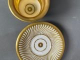 gold and white coffee cup and saucer with a spiral design