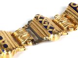 a close up of a gold bracelet with blue stones