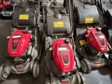 Plusieurs tondeuses à gazon sont alignées en rang dans un garage