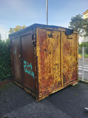 a rusted out dumpster sitting on the side of the road