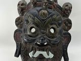 an image of a black mask with a face made out of wood