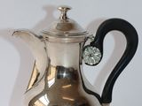 an image of a silver coffee pot with a black handle on a white surface