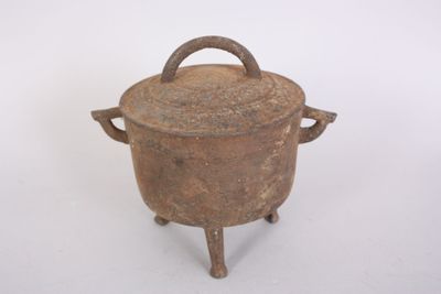 an old iron pot with a handle on a stand
