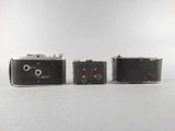 two old cameras sitting next to each other on a white surface