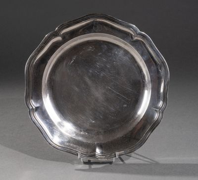 un plat ancien en argent posé sur un support, sur fond gris