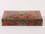 an old red and gold box sitting on top of a white surface