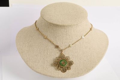 collier en or avec un pendentif vert autour du cou d'un mannequin