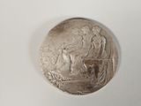 an image of a silver medal with a woman and two men