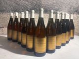 bottles of wine lined up on a table in front of a stone wall