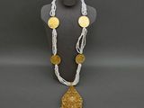 a white and gold necklace with coins and a gold pendant on a mannequin
