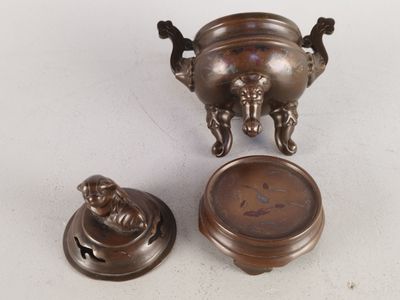une petite urne en bronze et une horloge posées sur une table