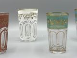quatre verres de couleurs différentes sont alignés sur une surface blanche