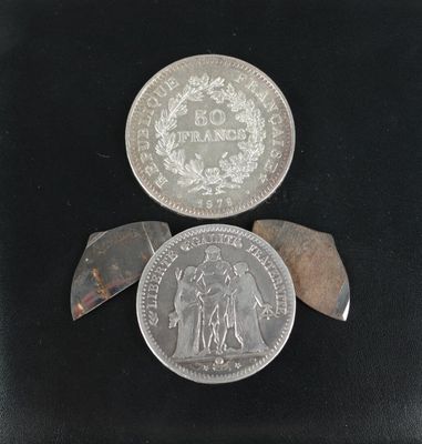 deux pièces d'argent et un couteau posés sur une surface noire
