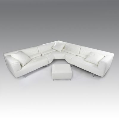 une photo d'un canapé modulable en cuir blanc accompagné d'un pouf