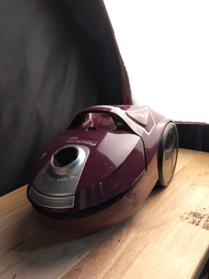 un aspirateur rouge et argent posé sur une table en bois