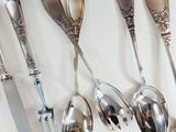several spoons, forks and knives are lined up on a white surface
