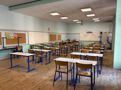 Il y a beaucoup de bureaux et de chaises dans cette salle de classe vide.