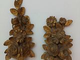 two gold vases with flowers on them on a white surface