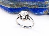 un gros plan d'une bague en diamant posée sur une pierre bleue
