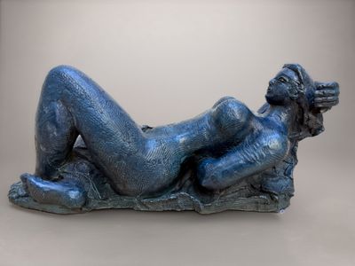 sculpture représentant une femme allongée sur un rocher, les jambes croisées
