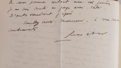 an open book with a handwritten letter on it sitting on top of a table