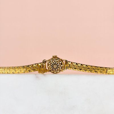 un gros plan d'un bracelet en or orné d'une fleur