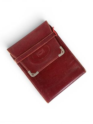 une photo d'un portefeuille en cuir rouge posé sur une surface blanche