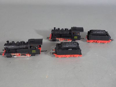 trois trains noirs et rouges posés sur une surface blanche