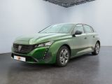 La voiture verte est garée dans une pièce blanche au sol noir.