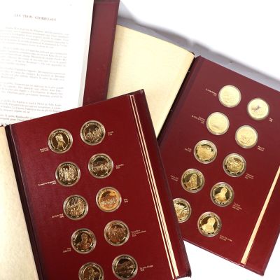 deux livres contenant des pièces d'or et d'argent, posés sur une table