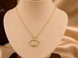 a gold necklace with a crown pendant on a mannequin